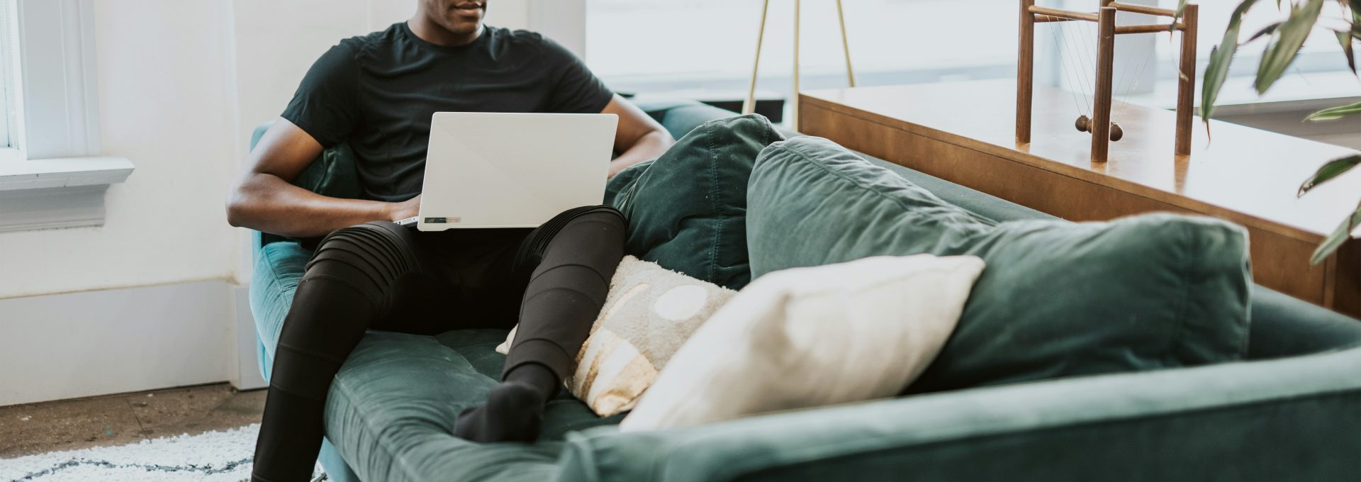man in black crew neck t-shirt and blue denim jeans sitting on gray couch
