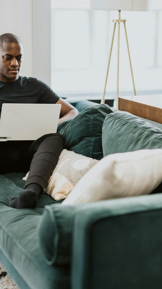 man in black crew neck t-shirt and blue denim jeans sitting on gray couch
