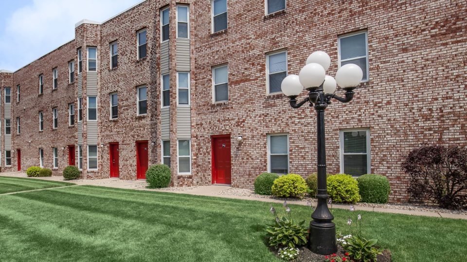 a brick apartment building with a lawn and grass at The Beacon Hill Apartments