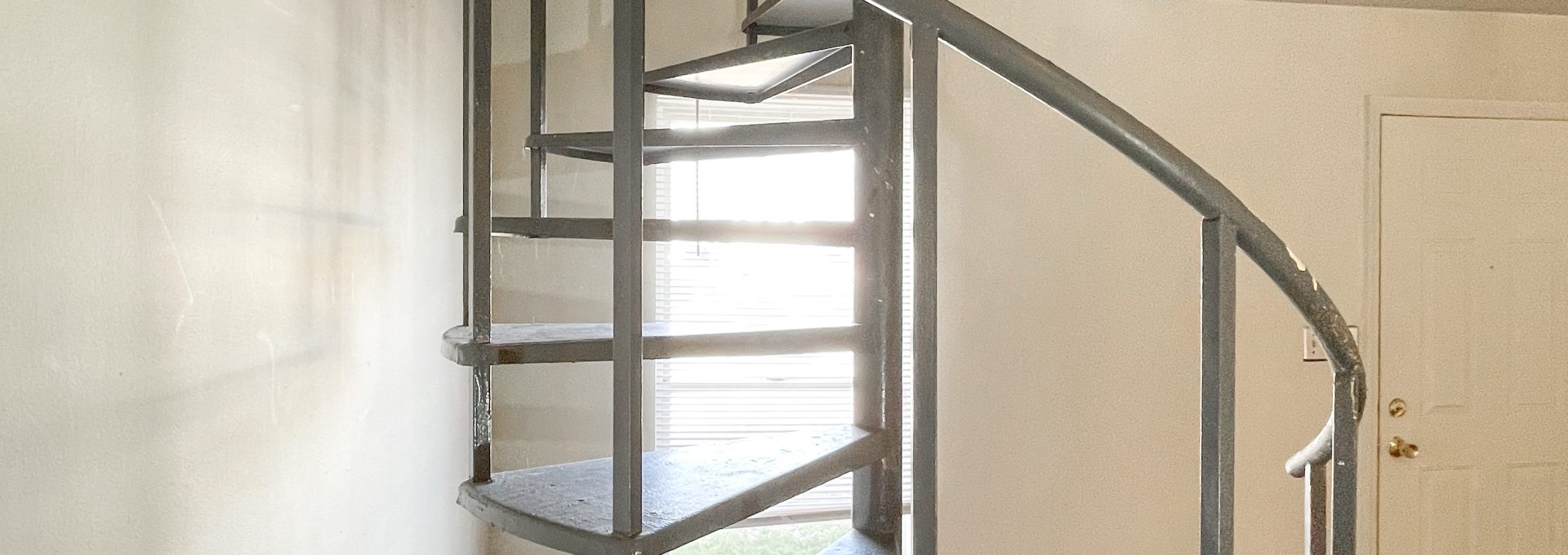 a spiral staircase in a small room with hardwood floors at The Beacon Hill Apartments